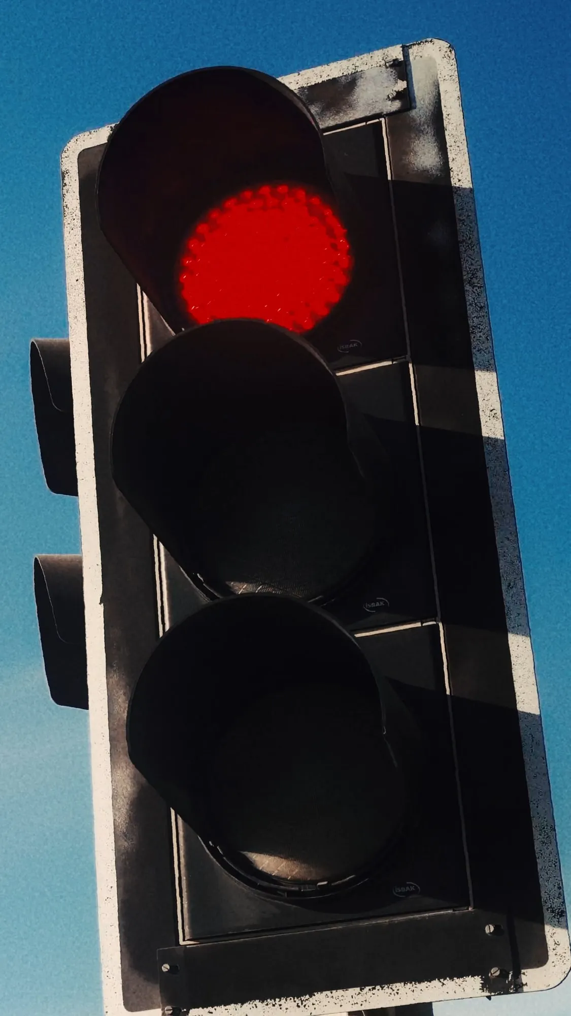 A still from the ad, a traffic light glowing red against a clear blue sky.